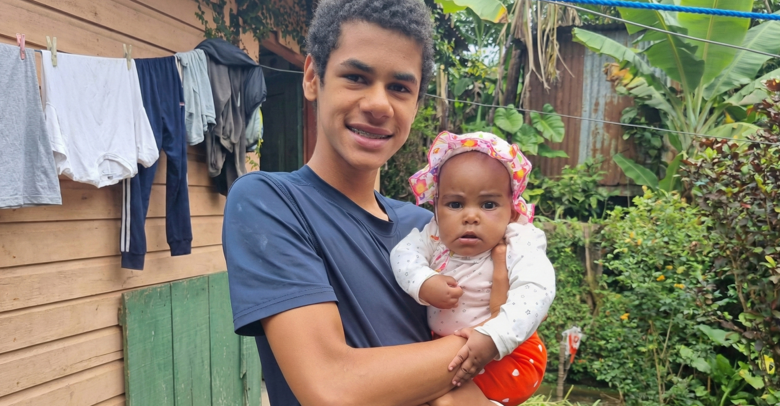 Chikima team member as a young boy holding a baby in Tanzania